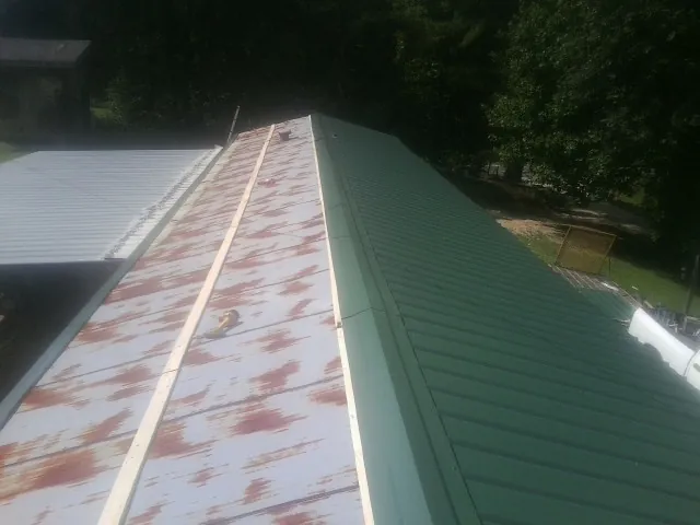 Old rusted panels beside newly installed green metal roofing — Wind Damage Roof Repair by Roofing Brothers in Vandergrift