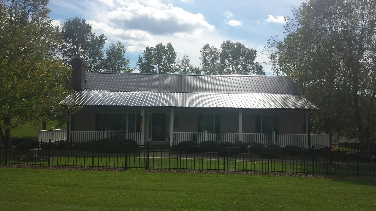 Gray metal roof on a brick ranch with a full width front porch — Gutter Guard Installation work by our crew in Vandergrift