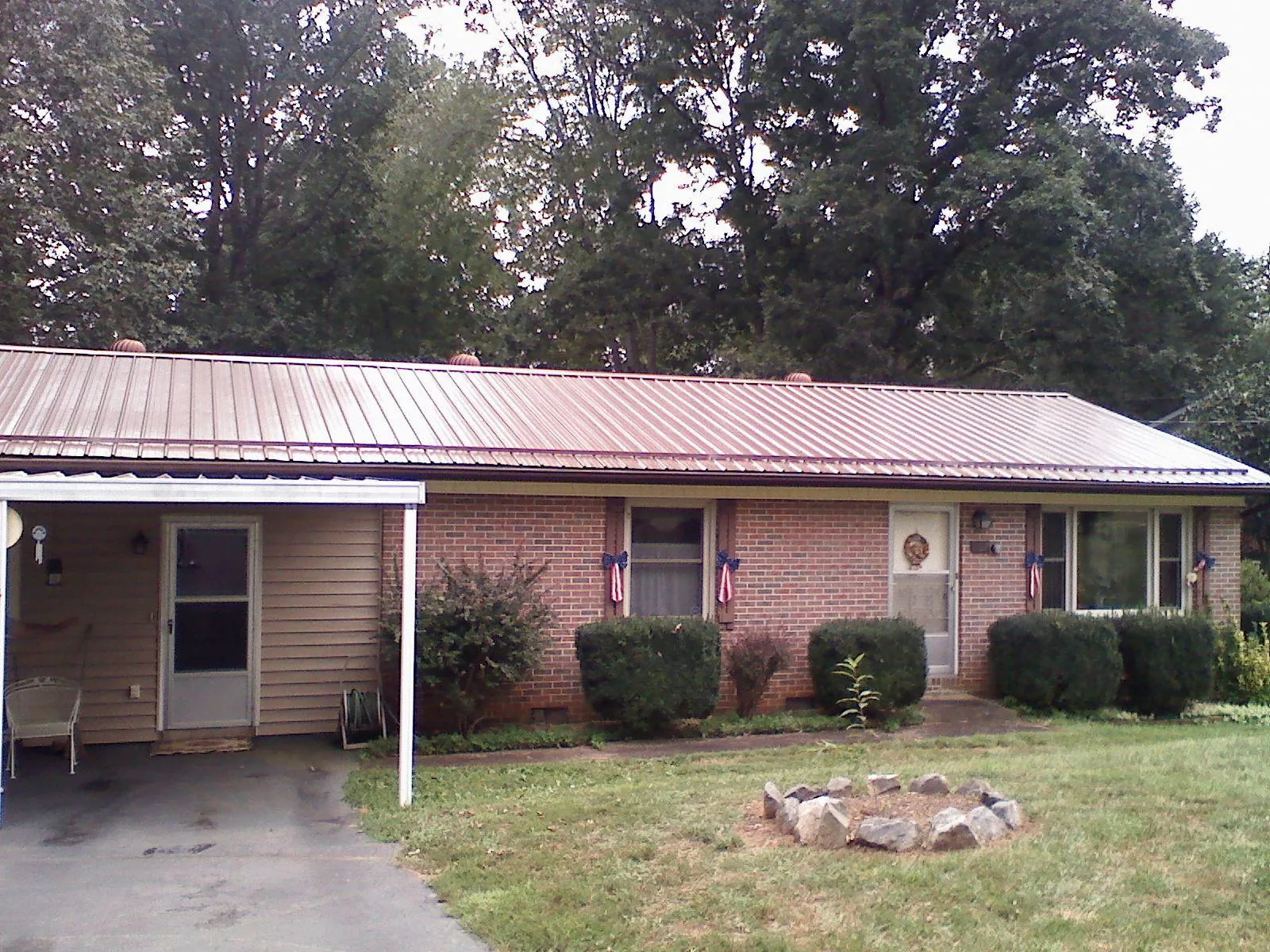 Bronze metal roof and carport on a brick ranch home — Roof Repair work by our crew in Vandergrift
