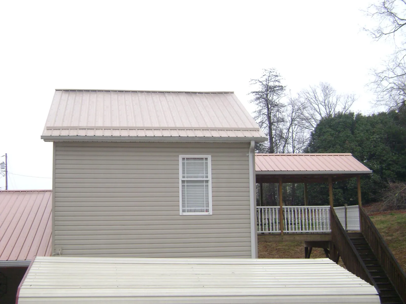 Tan metal roofs on a two story addition and attached porch, from a Roof Replacement job in Vandergrift