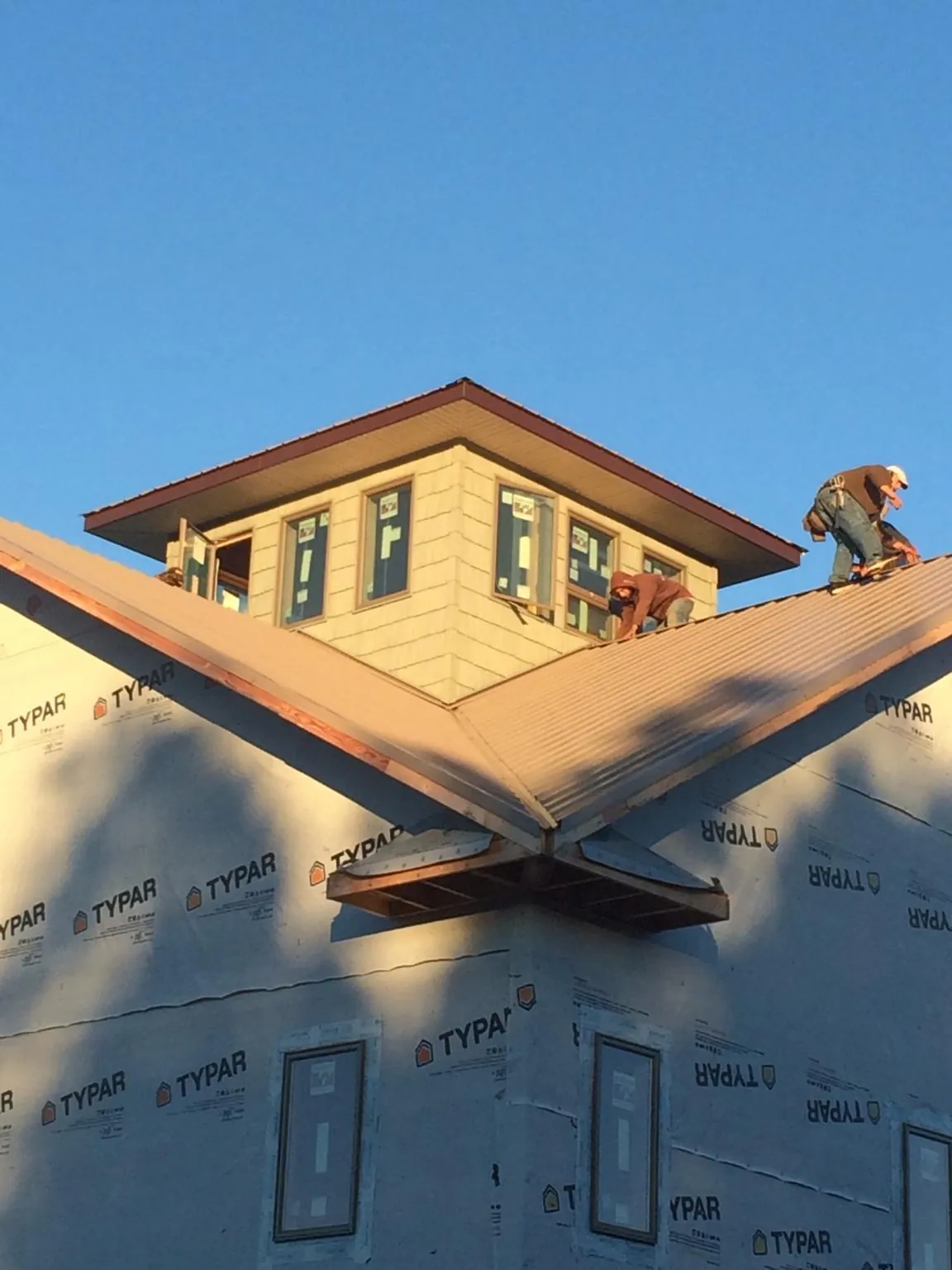 Roofers working around a rooftop cupola on a new metal roof at sunset — Roof Waterproofing in Vandergrift by Roofing Brothers